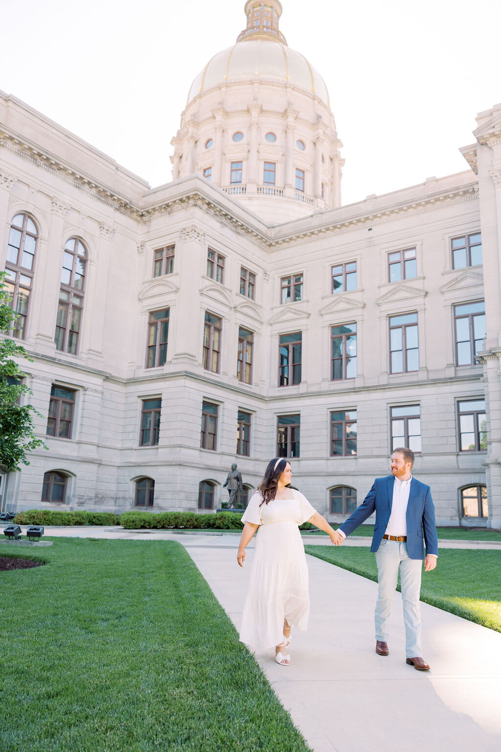 Engaged couple holds hands with Athens City Hall in background