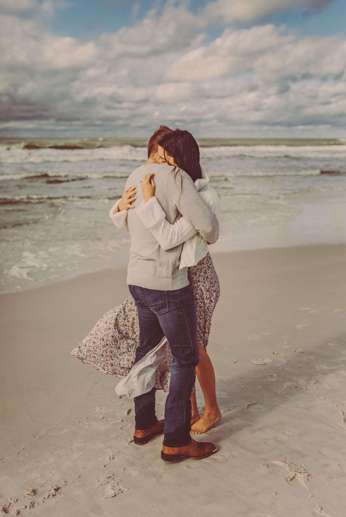 couple embraces on beach after surprise proposal