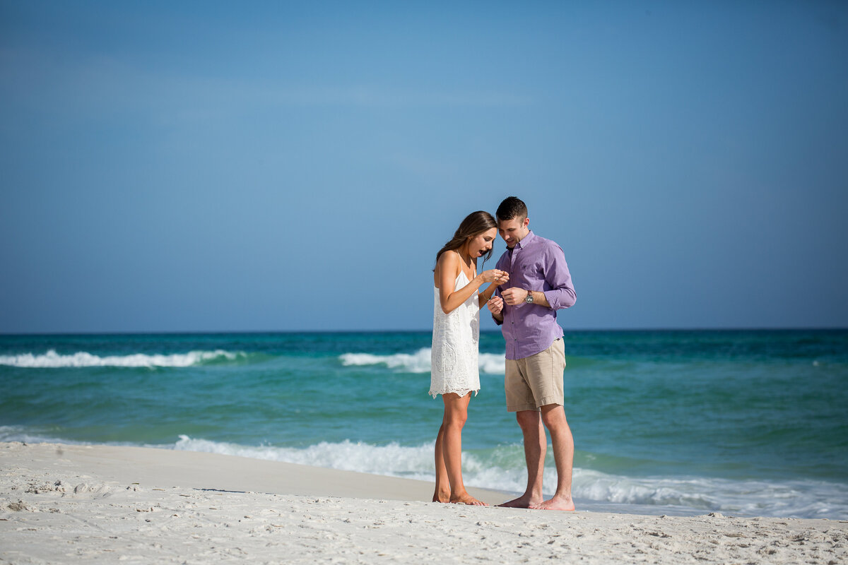 girlfriend inspecting the ring her new fiance proposed with on the beach at Rosemary.