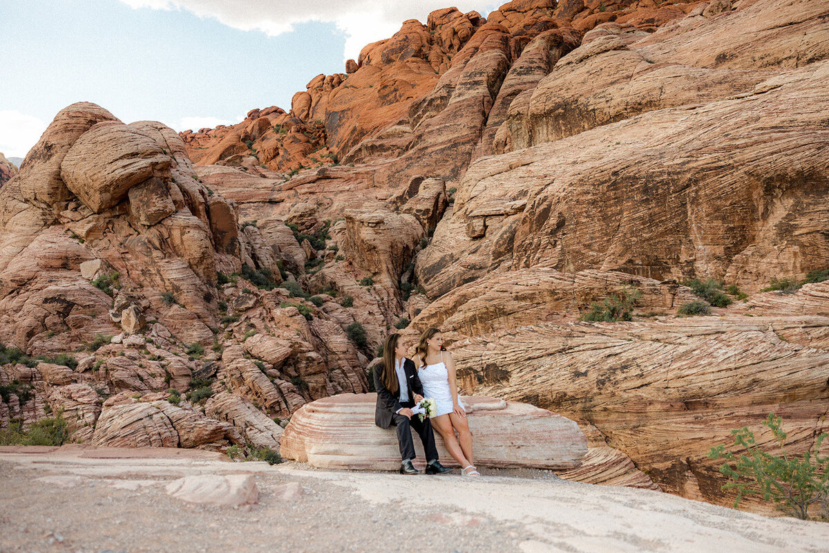 Engaged couple sitting on rock at the Red Rock Canyon smiling