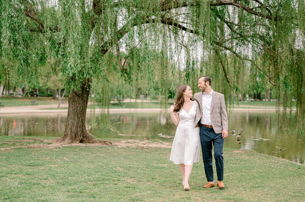Engagement photos of couple walking with willow tree behind them