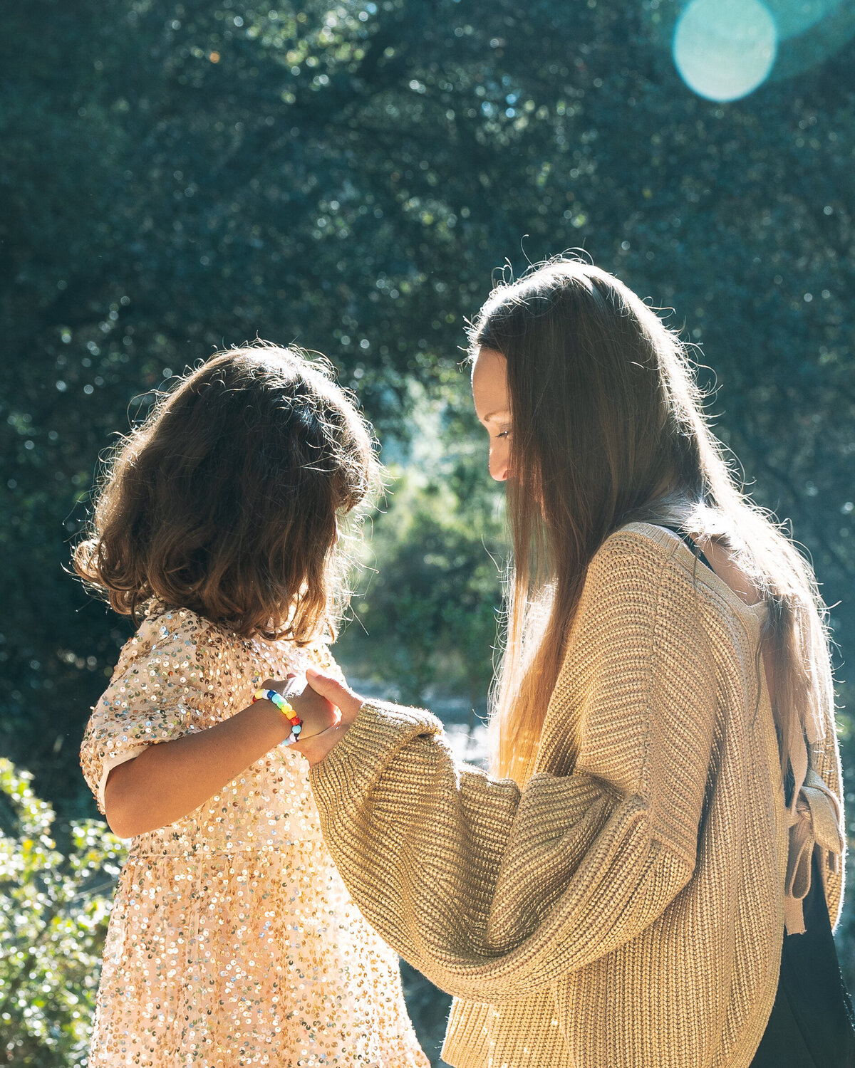 Mother and daughter hold hands with sun shining