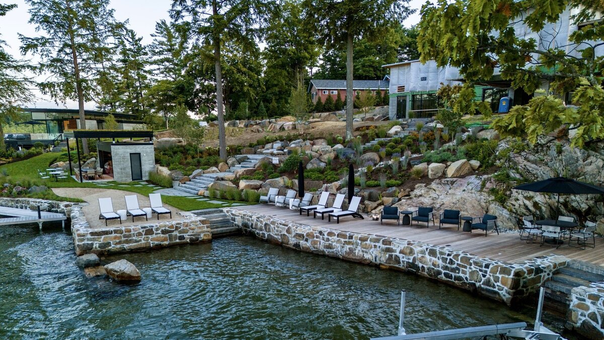 By the lake with lots of lounge chairs and path leading to main house