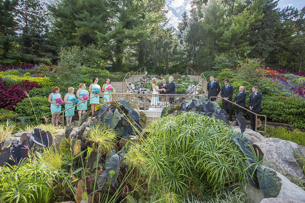 Bride and groom stand with their wedding party at Sunken Gardens