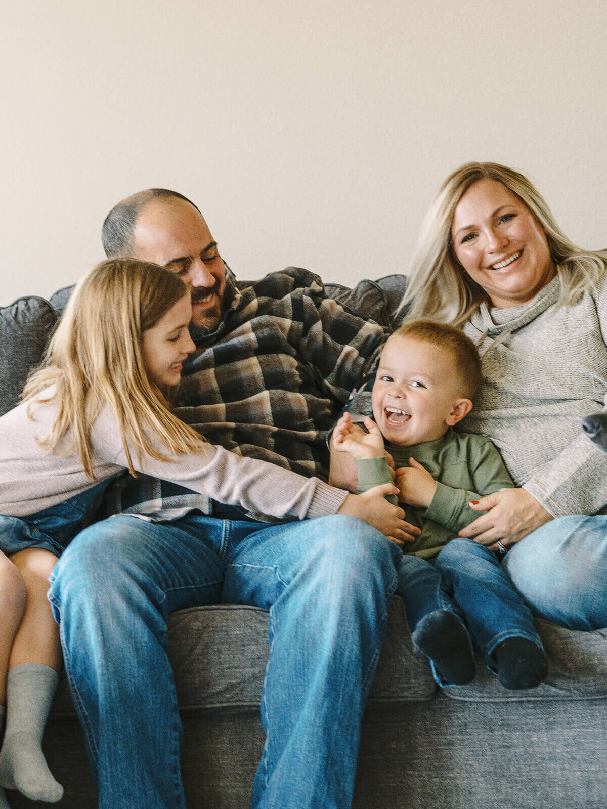 A family sits together on a couch during a family portrait photo session.