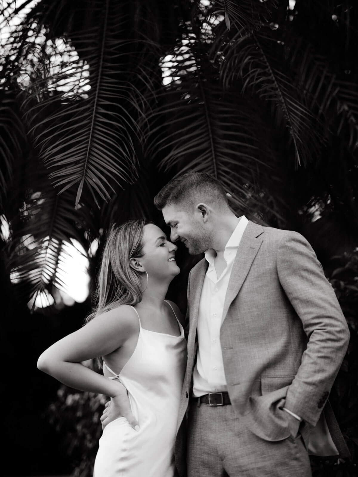 Black and white photo of the engaged couple standing close, happily facing each other in the garden of Round Hill Hotel, Jamaica.