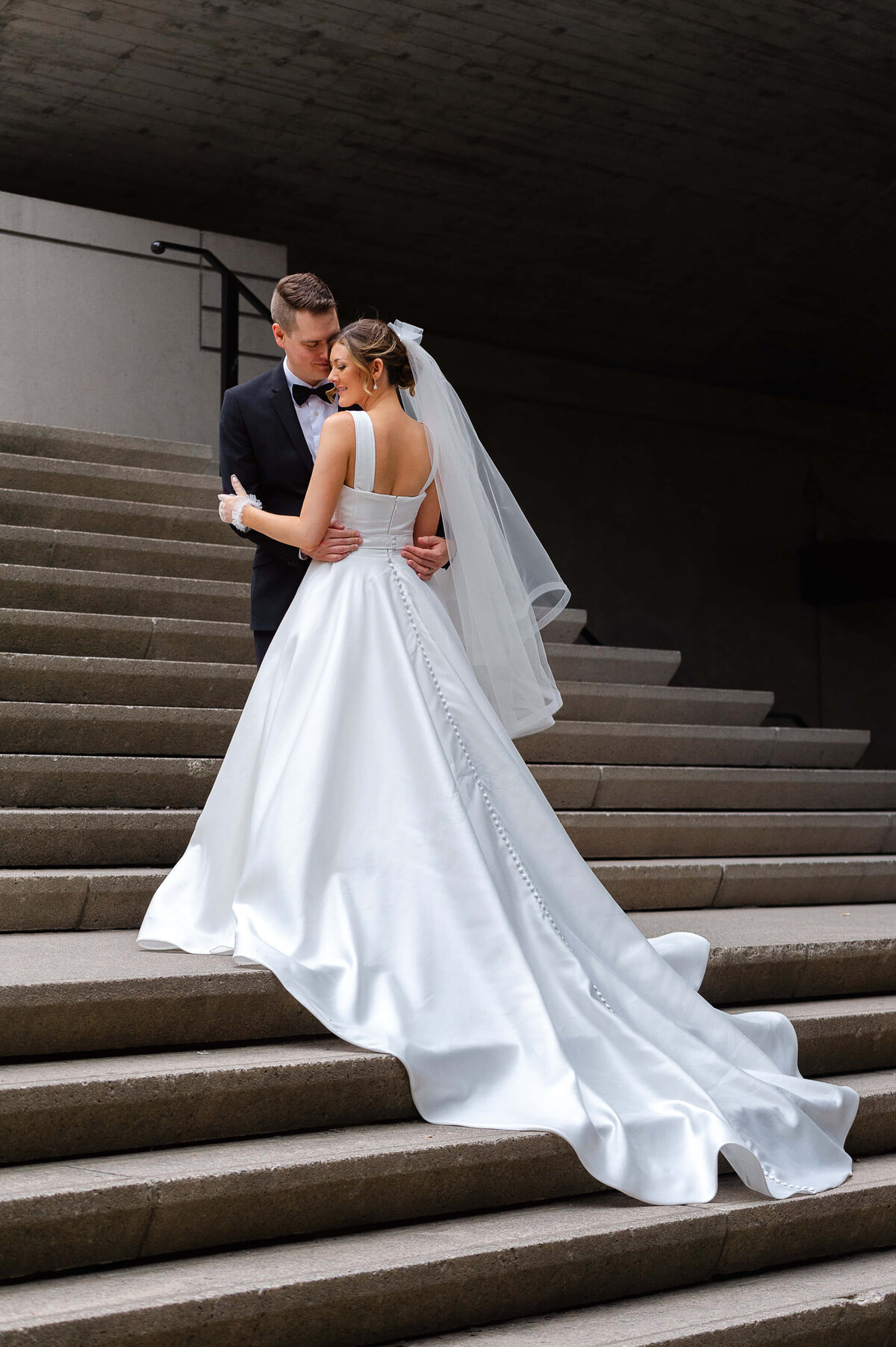 an intimate tull length photo of a bride and groom on the stairs of the Chateau Laurier underpass.  Captured by Ottawa wedding photographer JEMMAN Photography