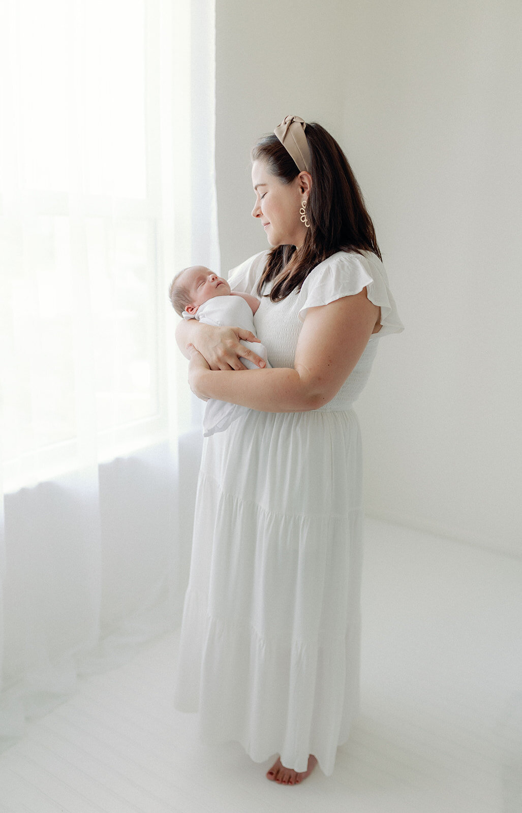 Mom carrying newborn baby by window