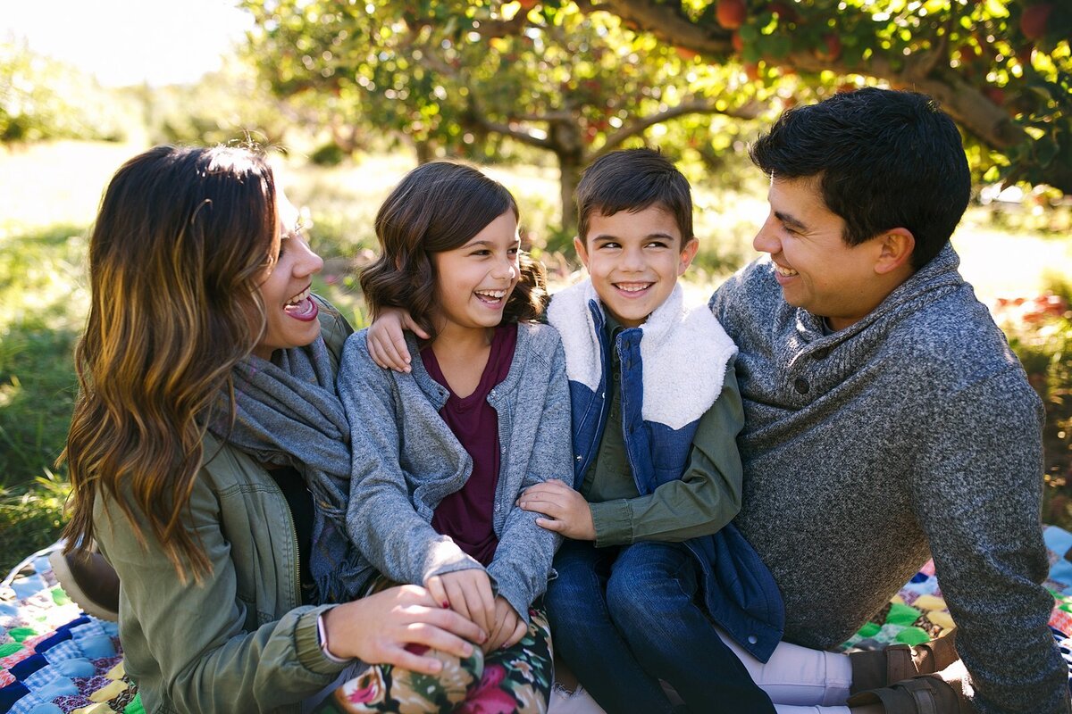 A-family-sharing-laughter-at-a-scenic-apple-orchard-on-the-south-side-of-indianapolis-during-a-fall-photo-session-celebrating-the-beautiful-autumn-colors-in-indiana