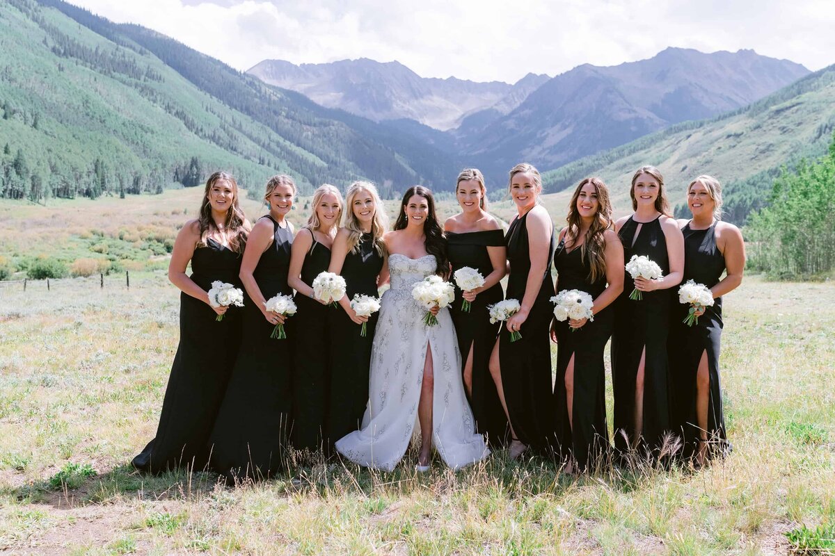 Bride wearing white and bridal party wearing black at an outdoor wedding in Colorado