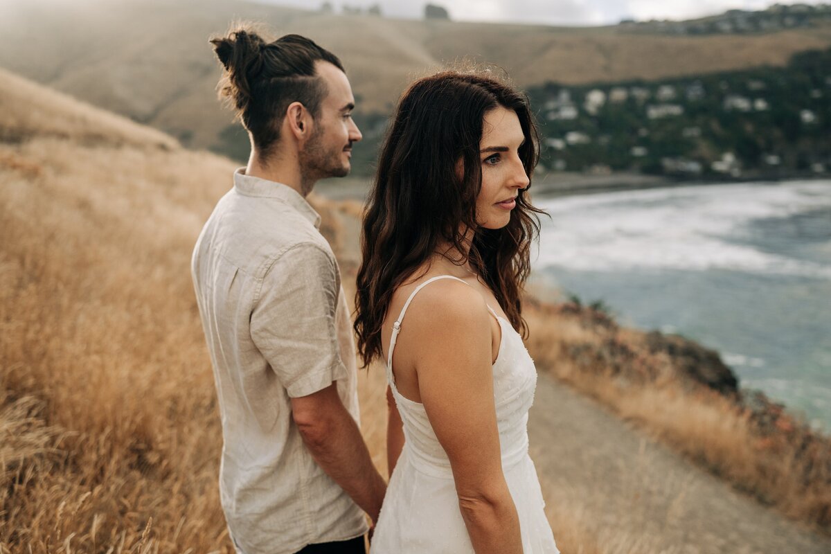 couple looking over bay at godley head at sunset