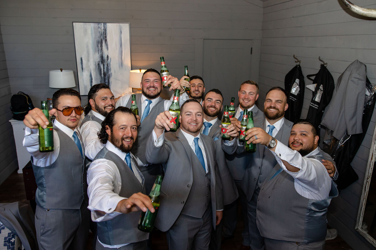 groomsmen salute photographer with Dos Equis in grooms suite at Morgan Creek Barn in Dripping Springs Texas