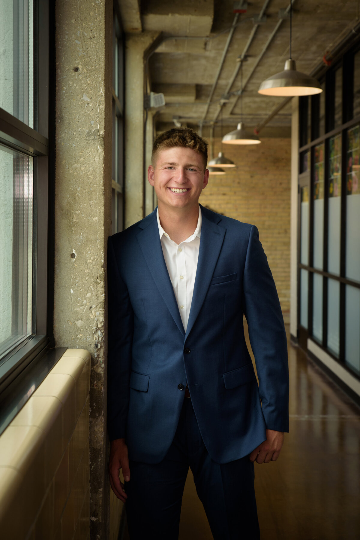 De Pere High School senior boy wearing a blue suit with white shirt standing in urban setting in Downtown Green Bay, Wisconsin