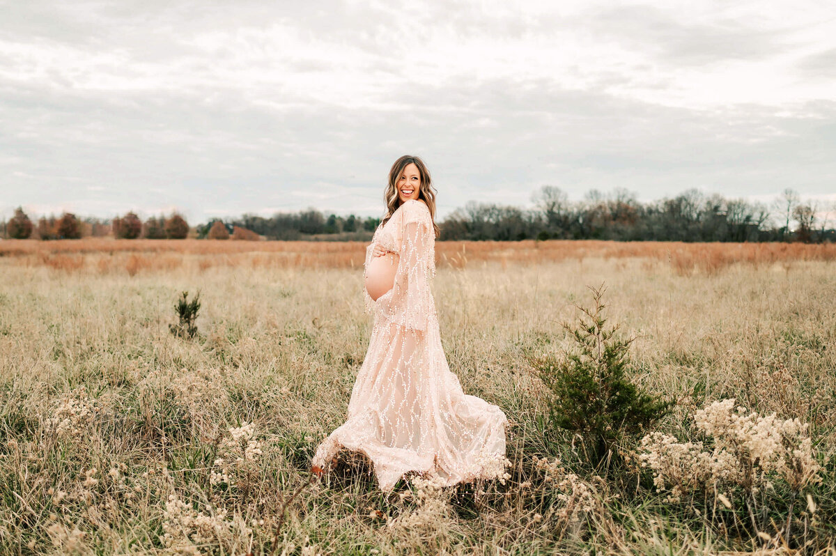 pregnant couple cuddling in field laughing in field captured by Joplin MO maternity photographer
