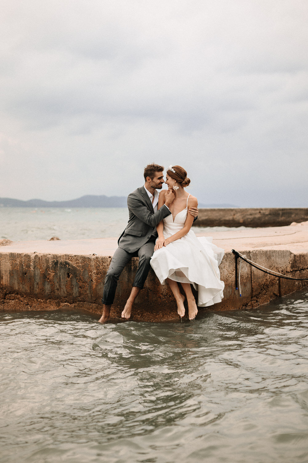 Brautpaar sitzt auf einem Steg am Meer in Kroatien