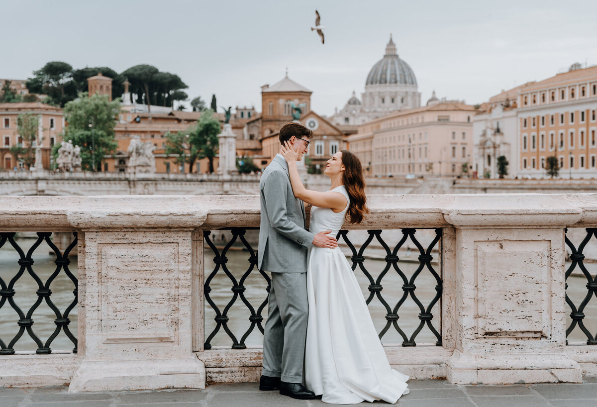 Couple smiling and holding each other on Roman bridge.
