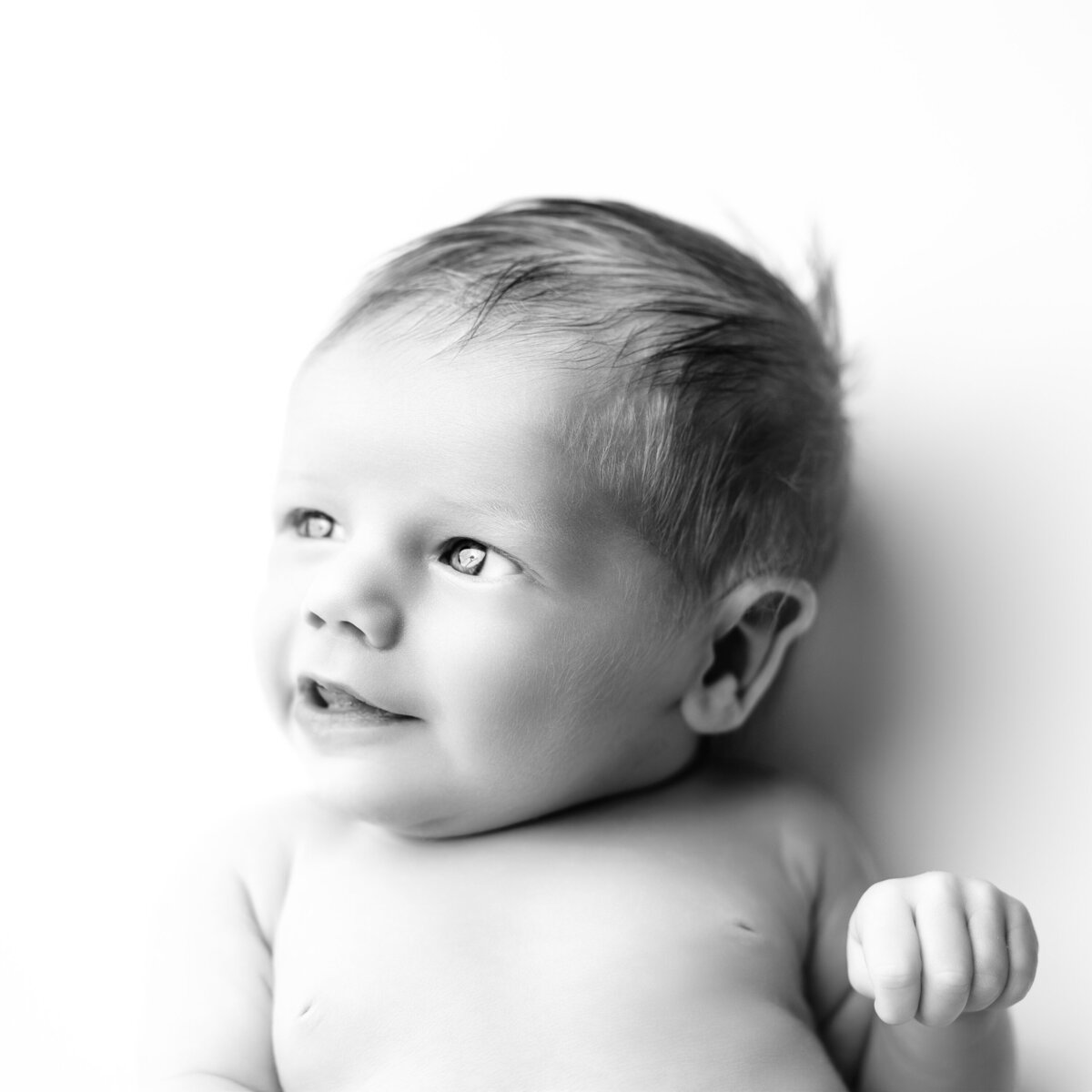This dreamy newborn profile portrait captures a soft smile and a peaceful mood, perfect for storytelling through subtle expression.