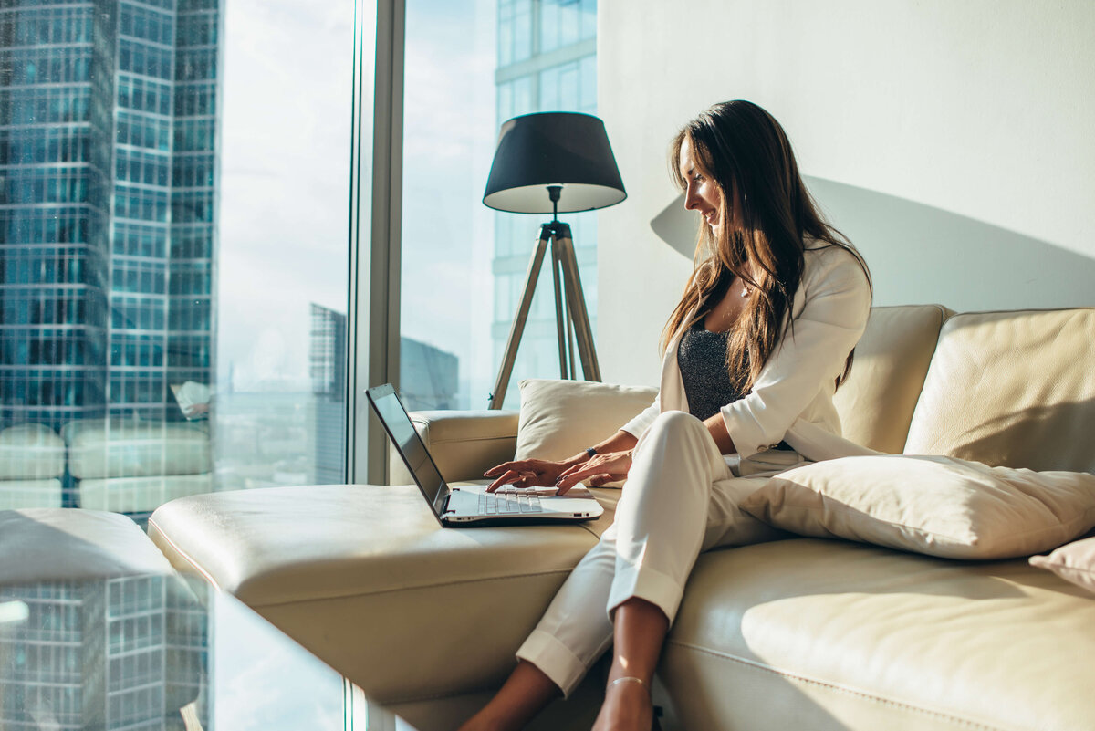 Professional woman in modern office looking at laptop—career clarity and coaching for high-achievers