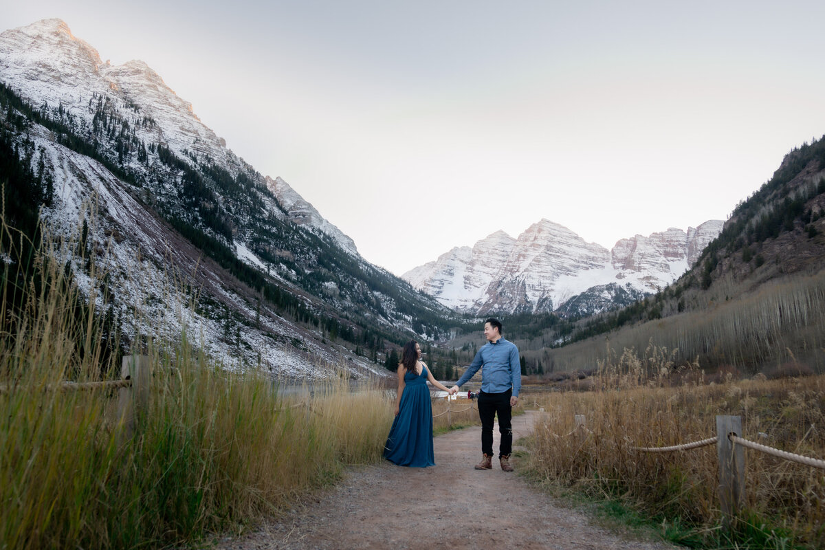 Maroon Bells Colorado elopement with Asian couple by snowy mountains and lake holding hands.