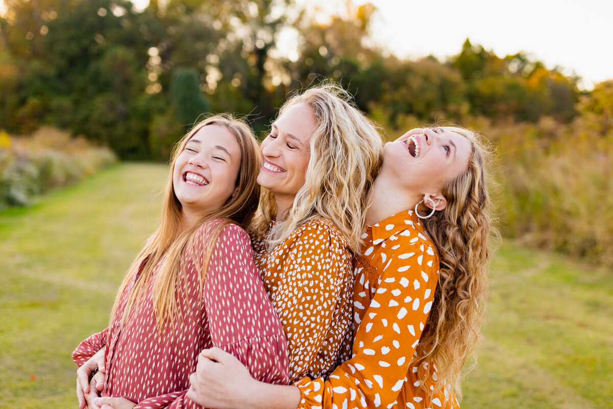 Mother and her two daughters hugging and laughing together in a field