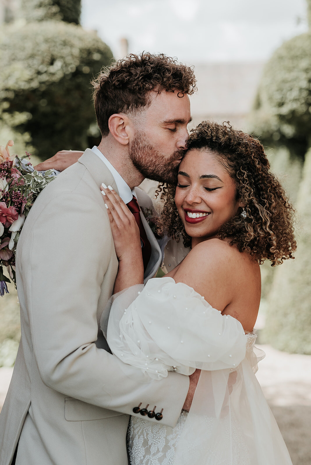Groom kisses his Bride on the cheek as she smile softly at their wedding at Euridge Manor