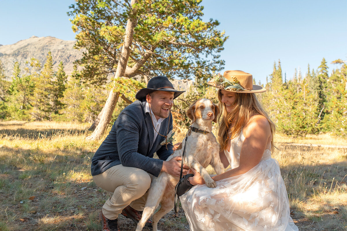 Bride and groom smile with their dog at their elopement