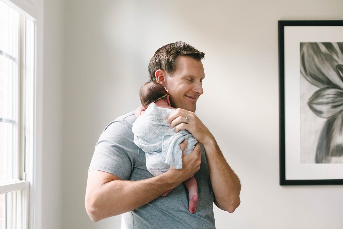 father holds newborn baby in arms