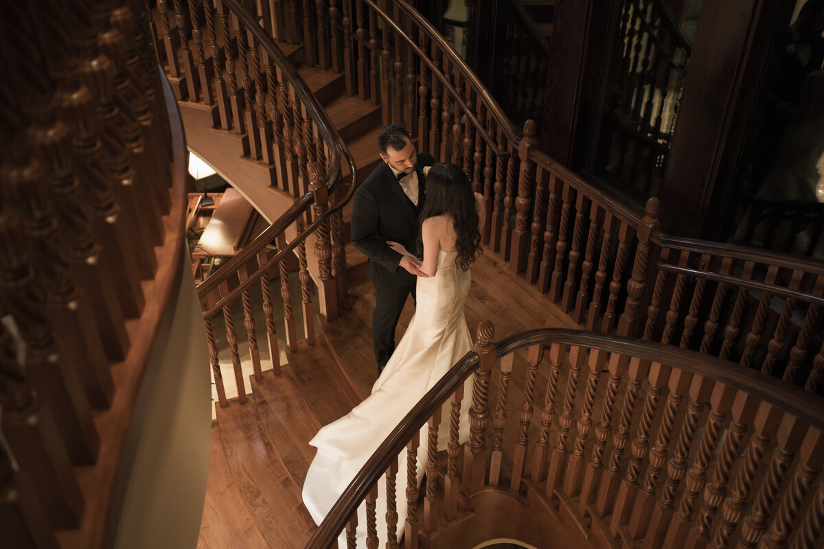 newlyweds at top of stairs look at each other