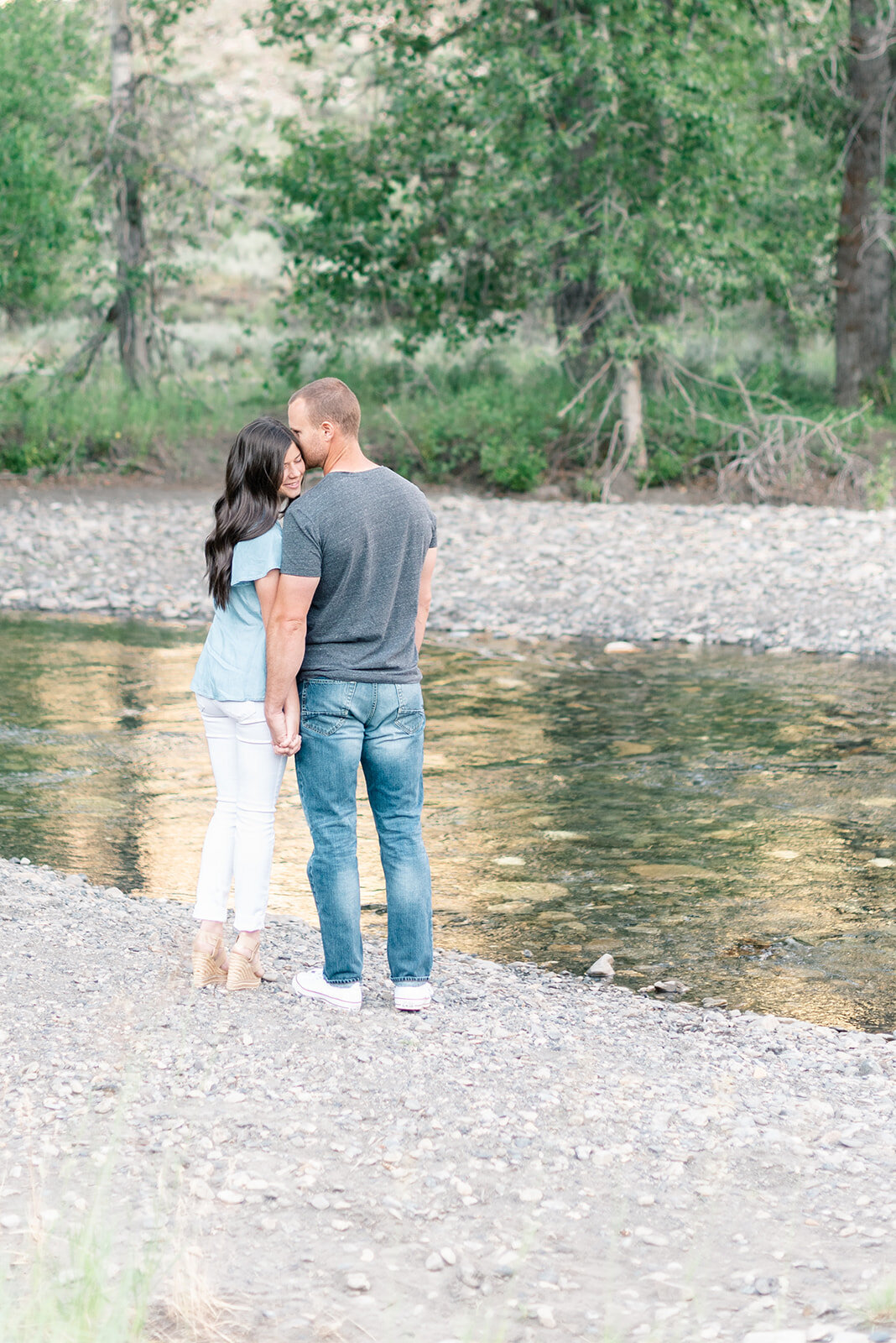 Couple standing next to a river holding hands at Sun Valley Engagement Session with the Best Sun Valley Wedding Photographers