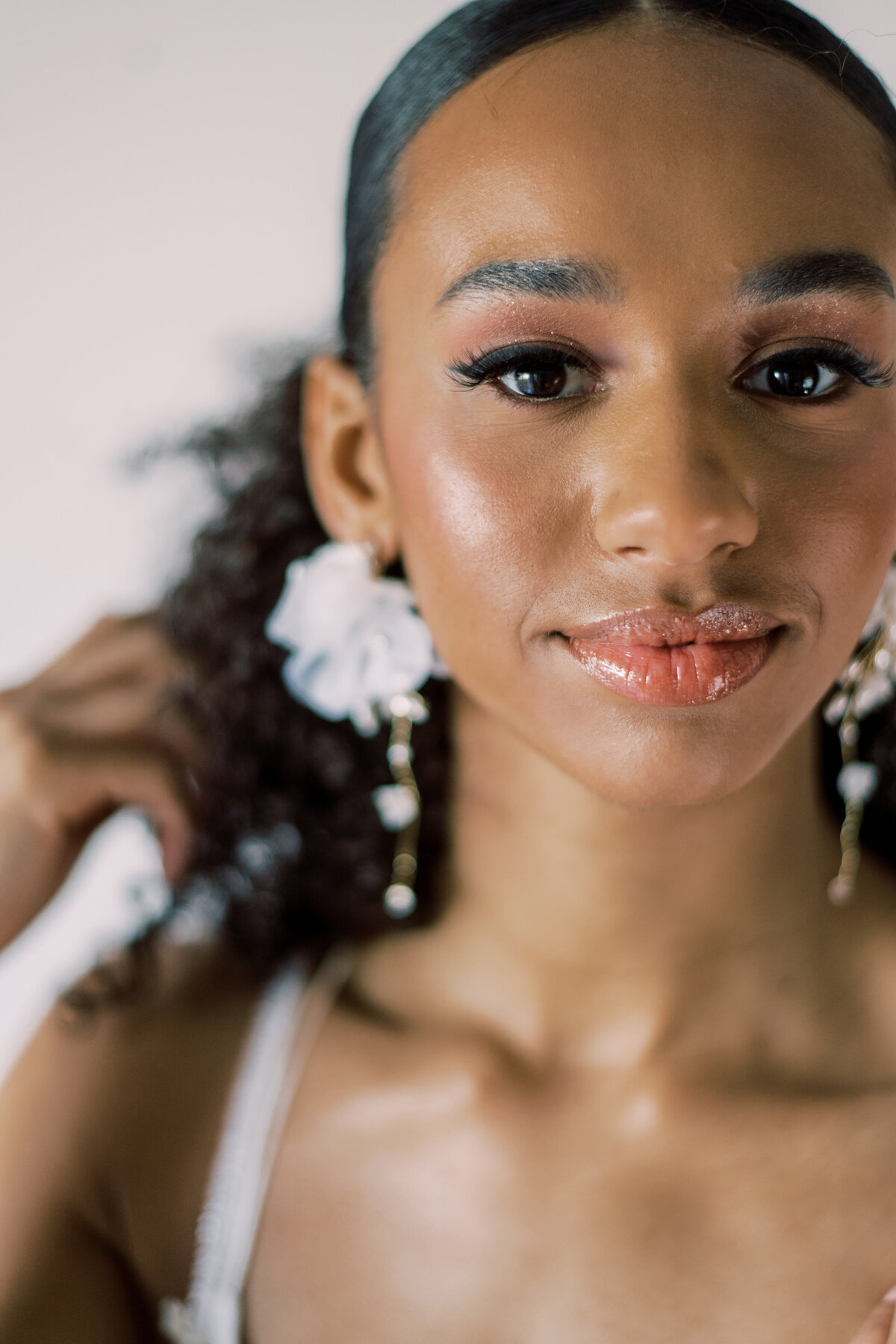The bride's delicate hand adorned with floral earrings , a close-up by Christine Grace Photography in Toronto.