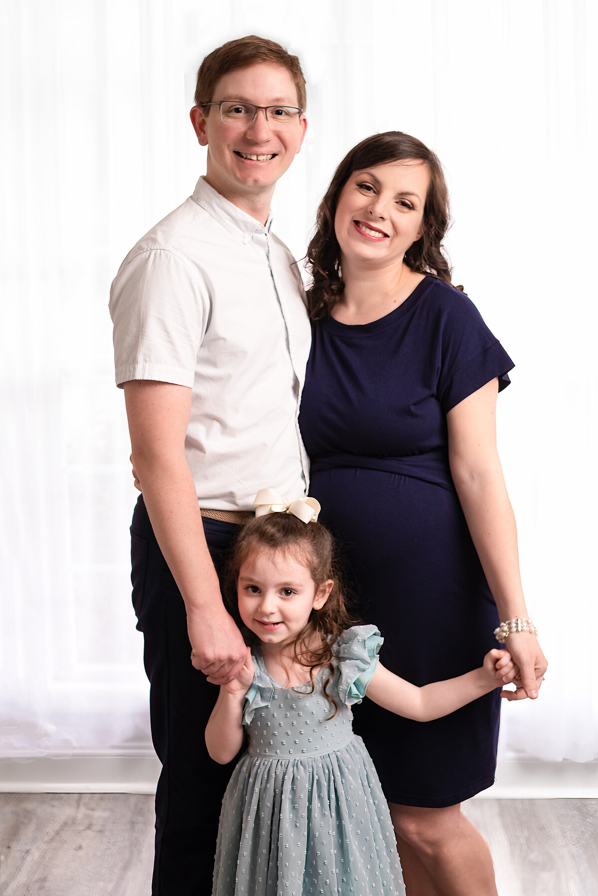 A mom and dad pose with their young daughter for family pictures in Huntsville Alabama