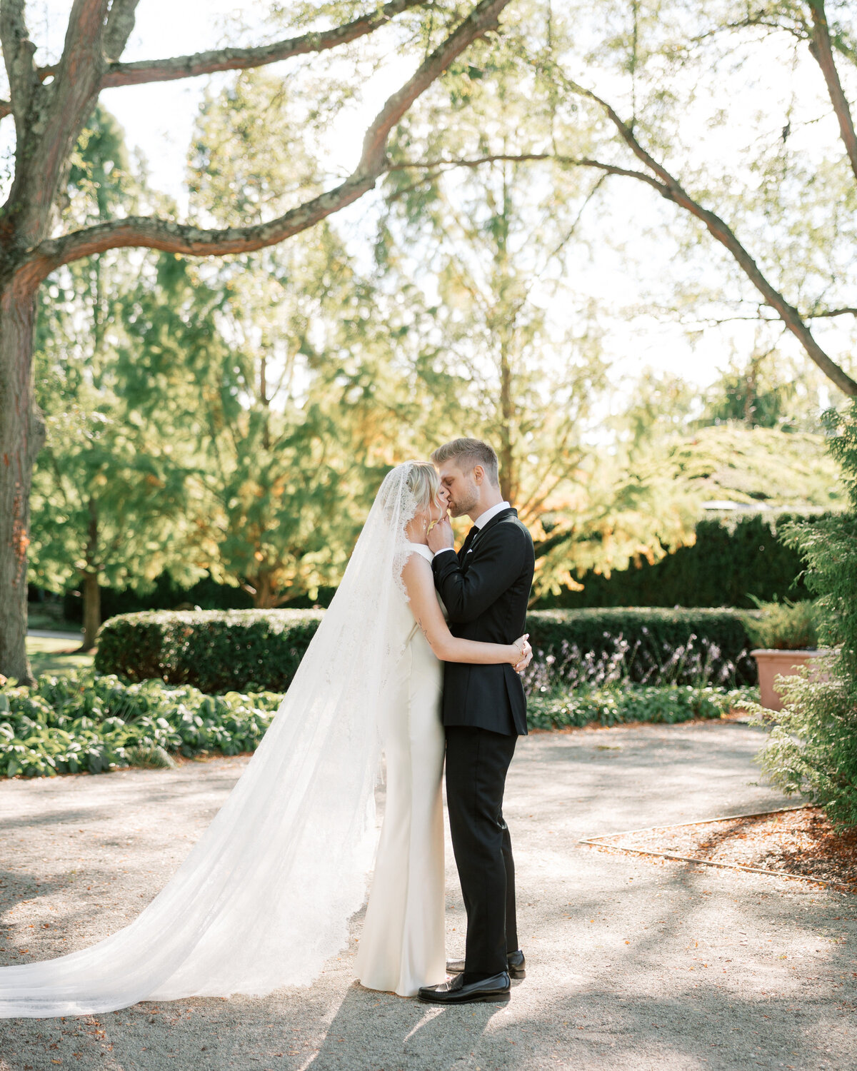 Bride and groom embrace under trees in Dayton, Ohio, romantic moment captured by Philadelphia wedding photographer.