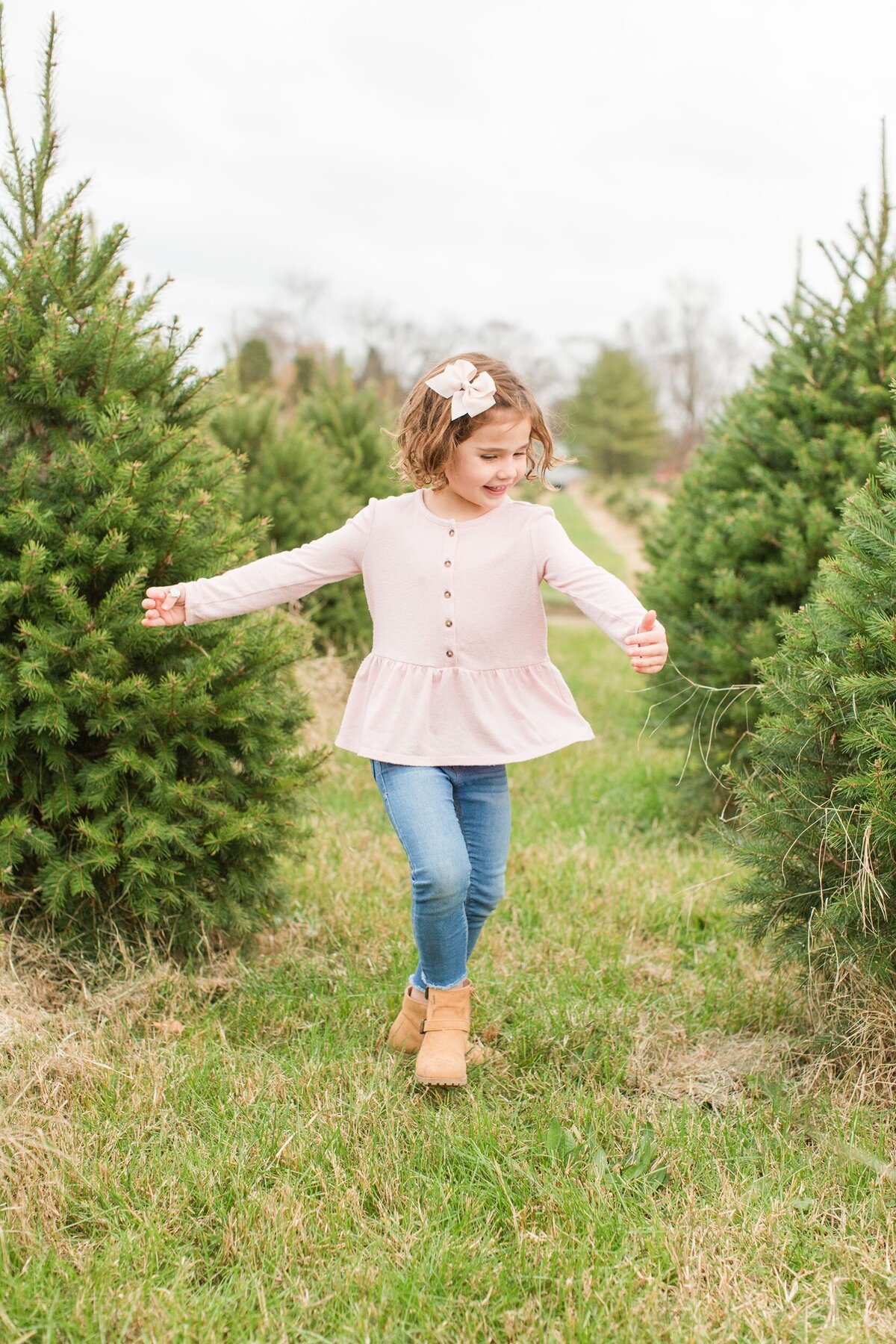Young girl skipping through Christmas tree farm