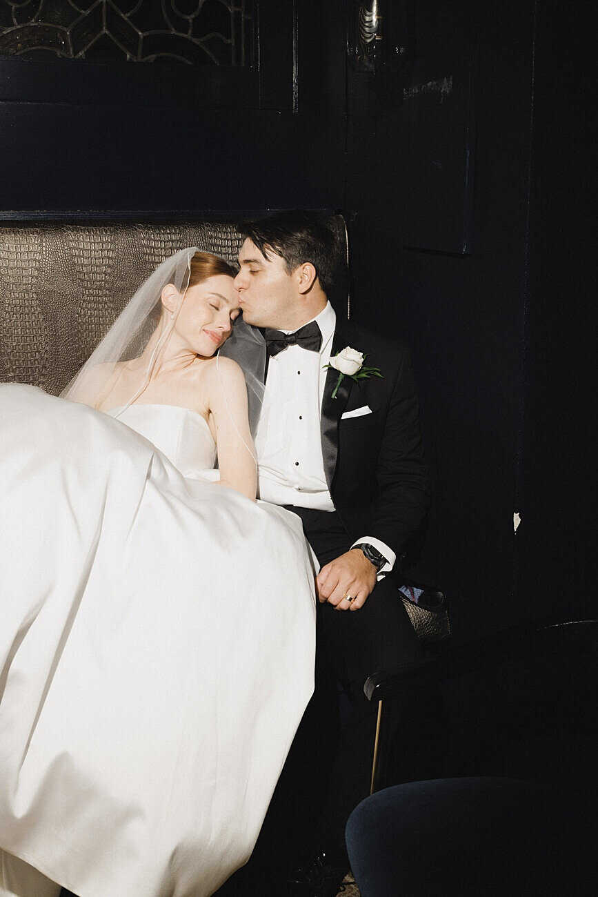 bride leaning back on groom as he kisses her forehead