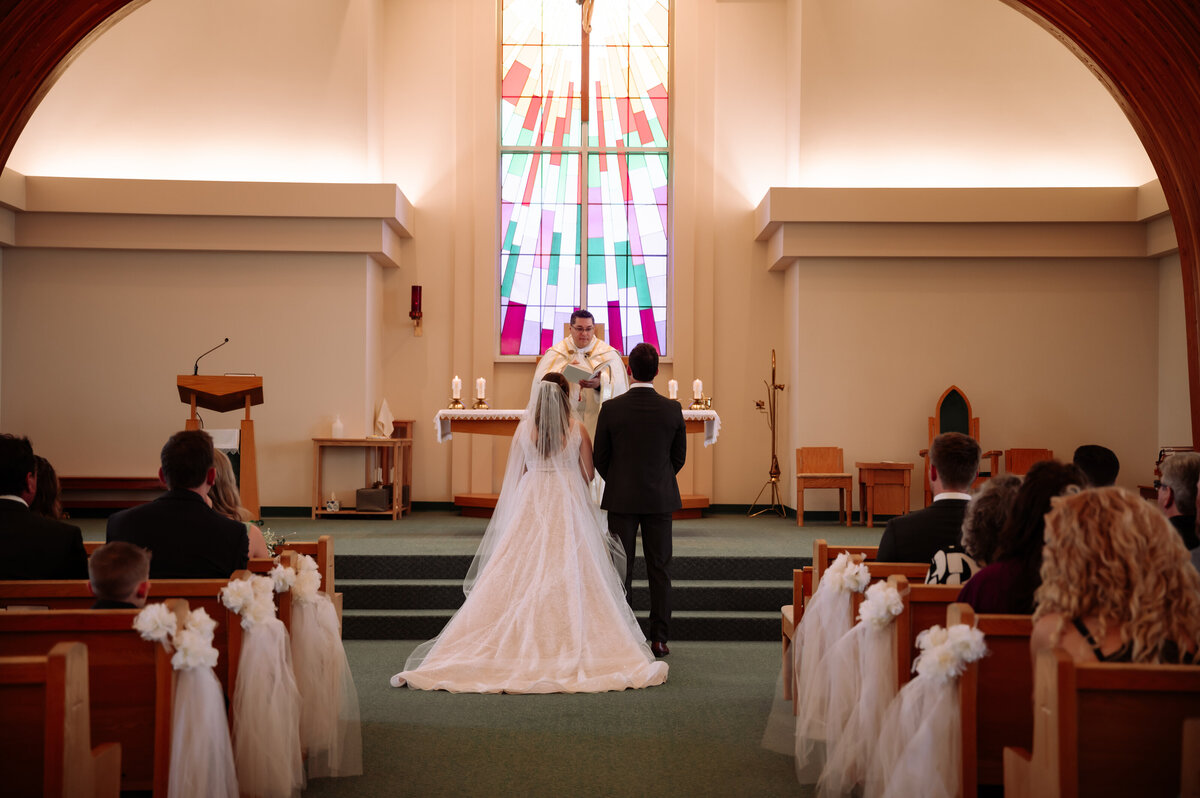 bride and groom in bright white church in Edmonton, Alberta sharing vows