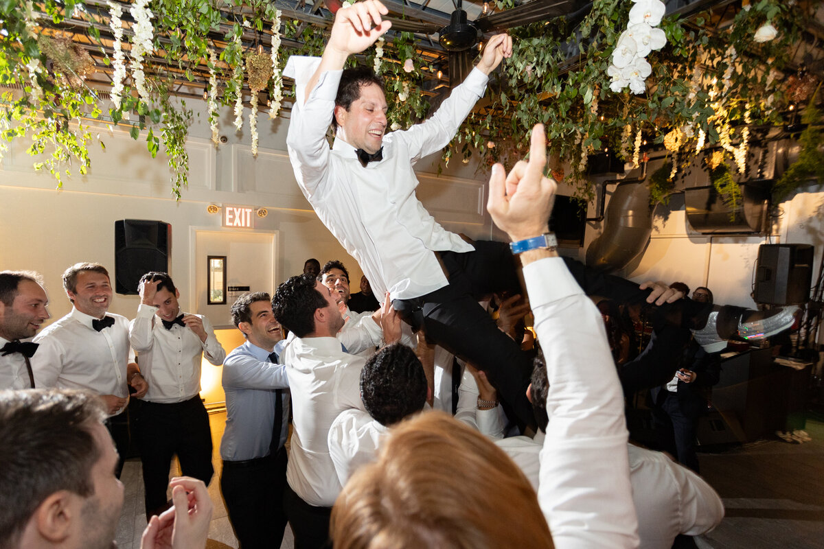 mark is tossed in the air by his friends during the wedding reception