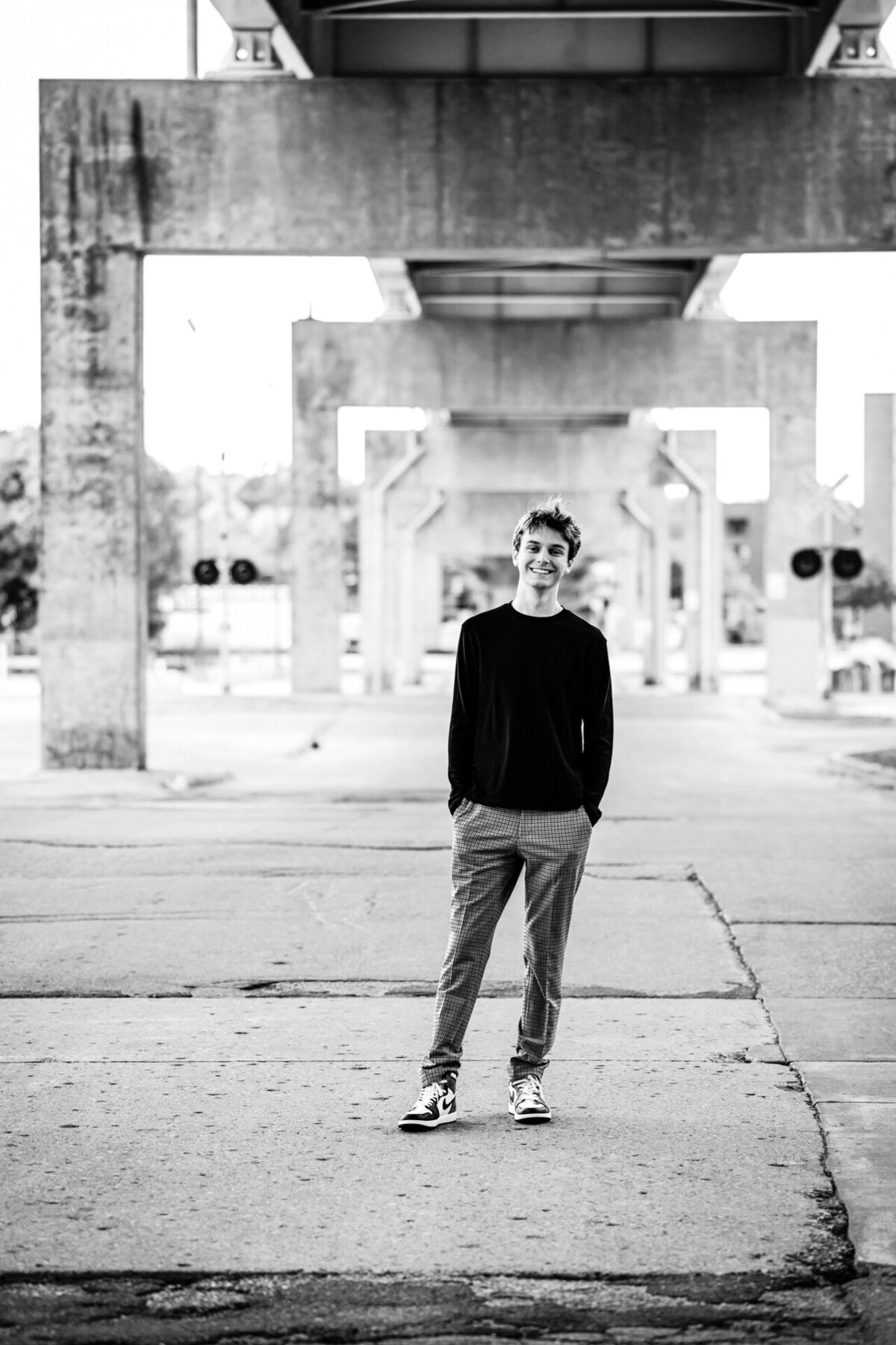 Black and white portrait of a senior boy in an urban setting, confident and moody.