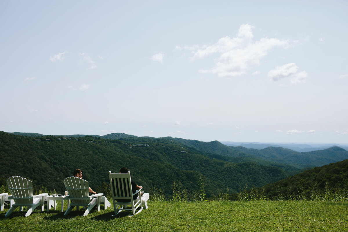 family sits in Adirondack chairs on top of North Carolina mountains