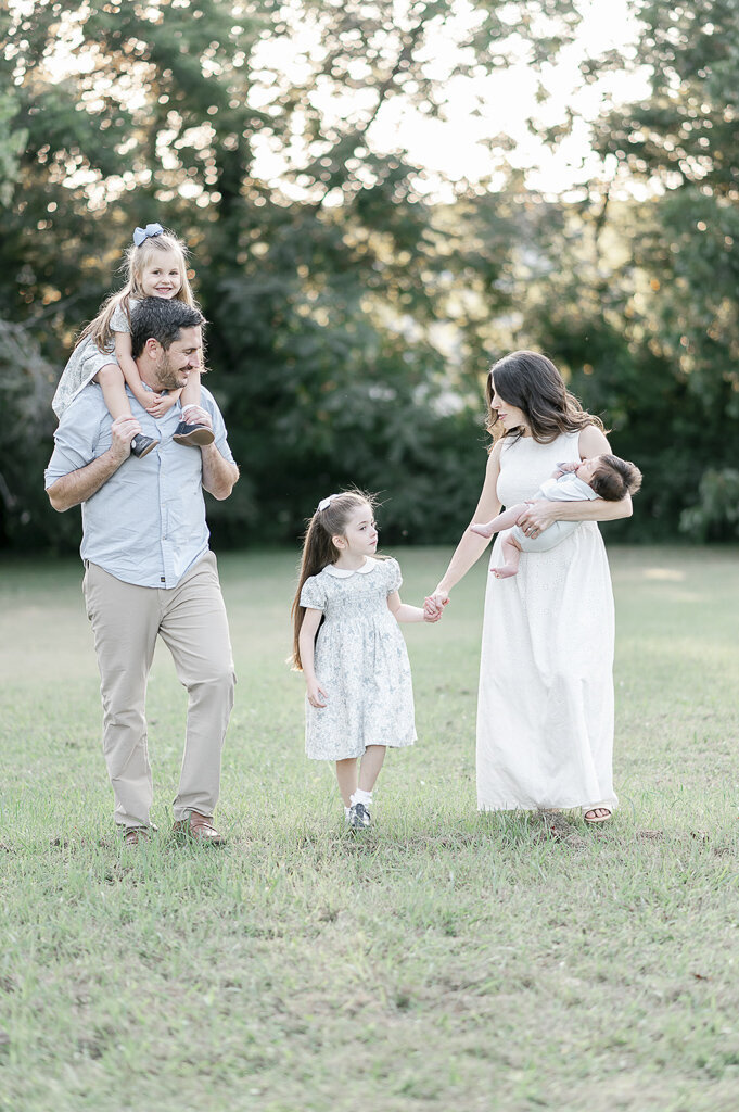 Family of 5 walk in the grass holding hands