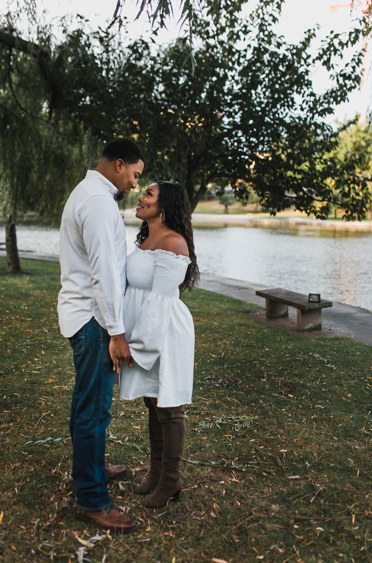 Pregnant woman and man hold hands and look face to face.