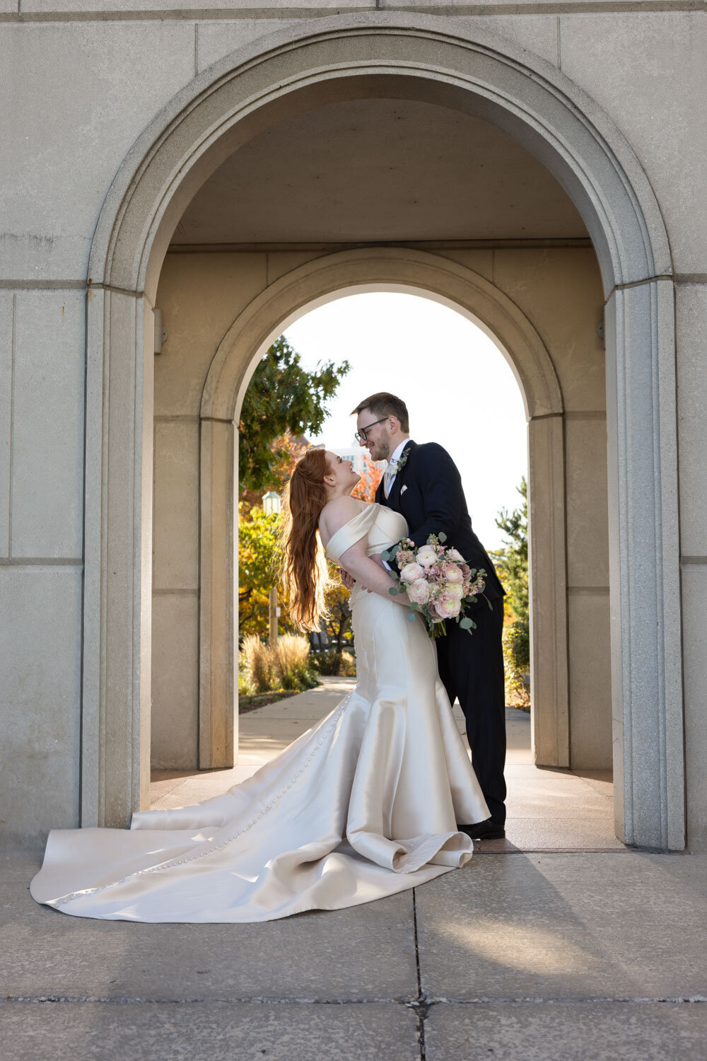 Bride and groom about to kiss under an arch