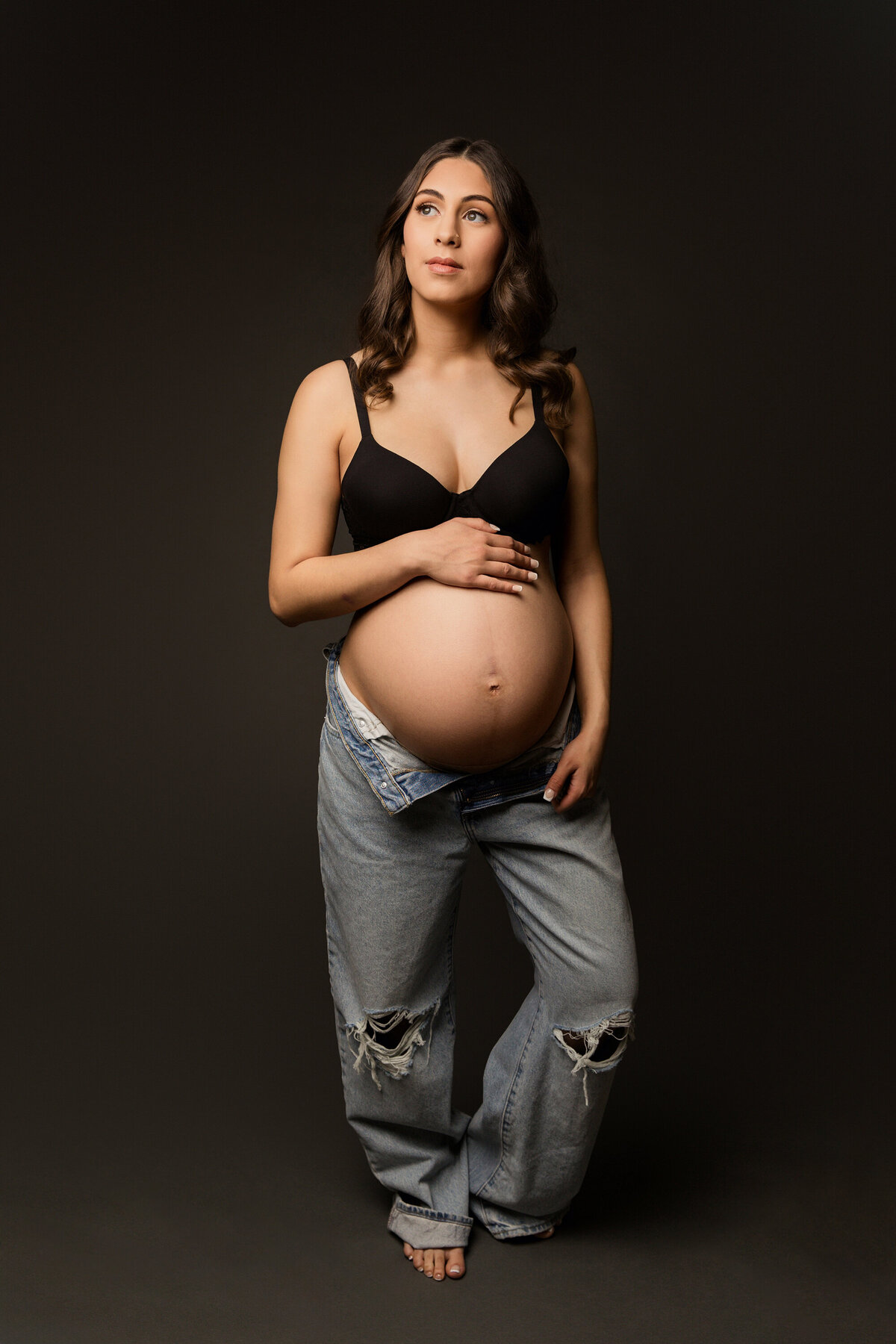 mother in jeans and bra in maternity studio for maternity session in phoenix maternity session