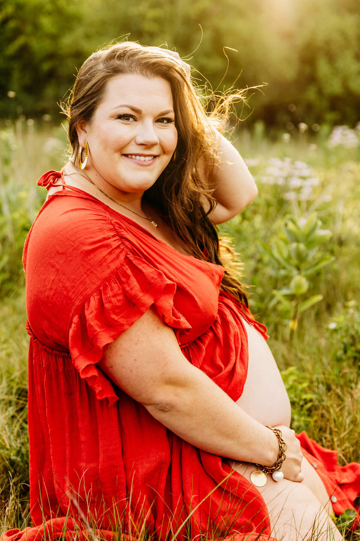 stunning mom holding her bare bump in a field during maternity photo session
