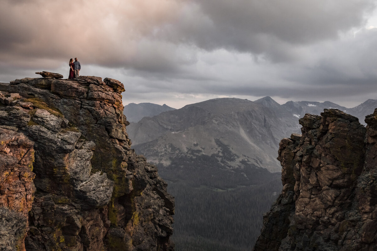 A couple stands on a cliff in Rocky Mountain National Park in Colorado