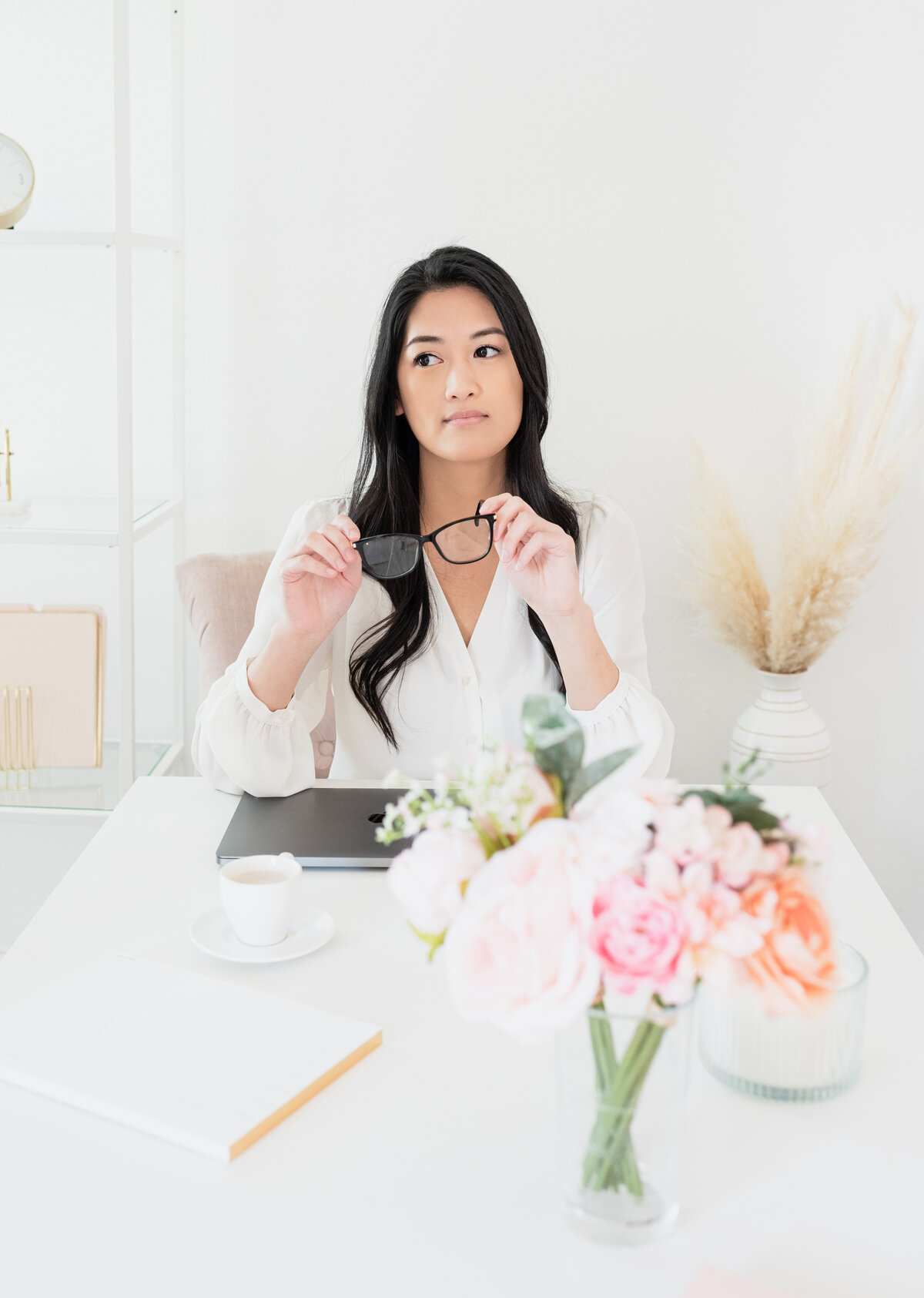 concerned entreprenuer Thinking at her desk with a bouquet of flowers in front of her