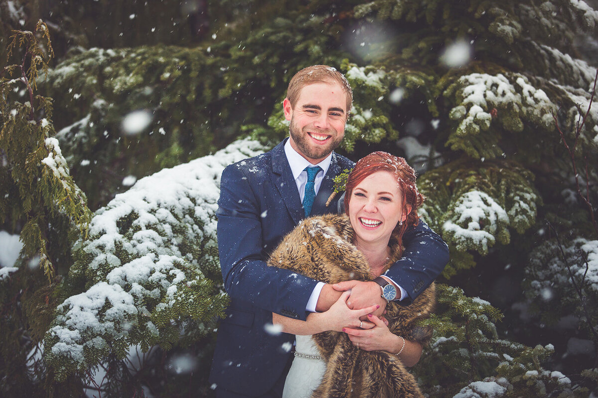 Bride and groom embracing in the snow on their wedding day.