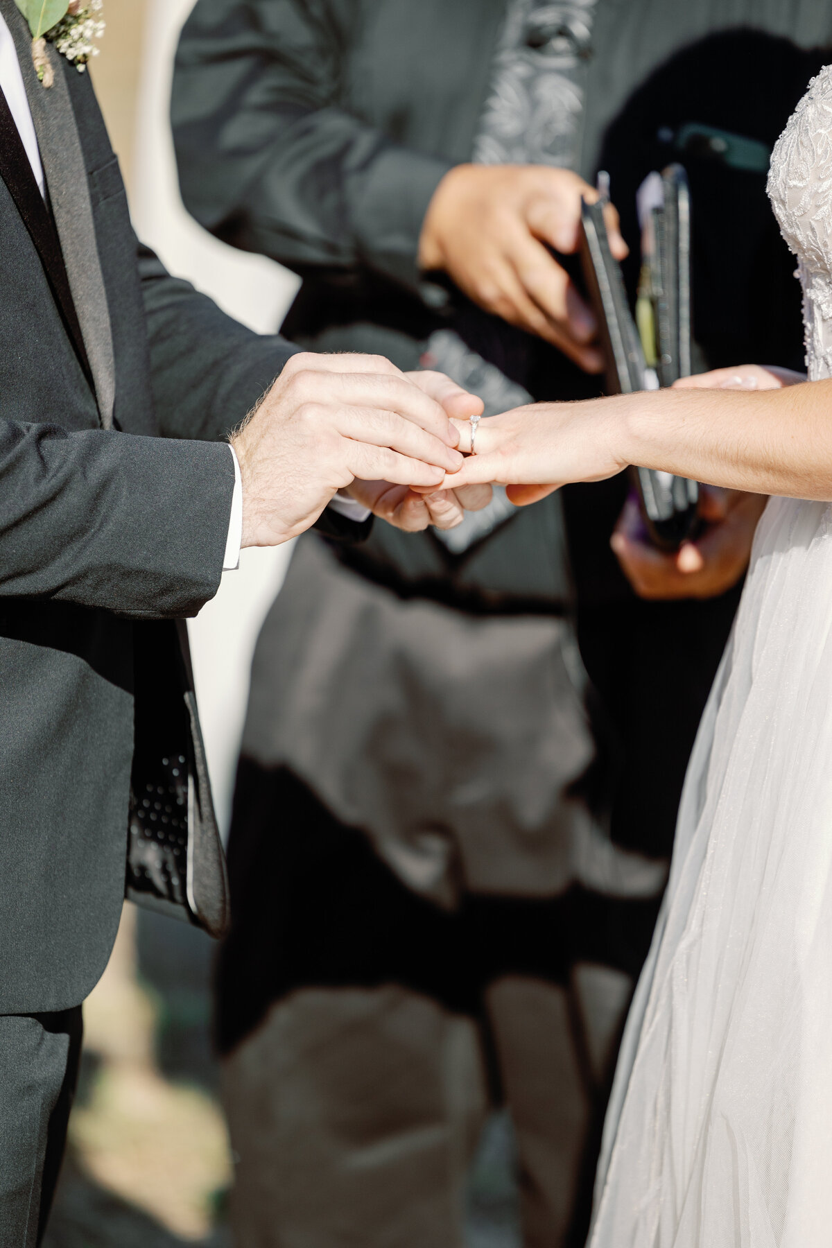 wedding photographer bay area captures the moment the groom puts his bride's wedding ring on during their outdoor wedding ceremony at Rosewood Events in Petaluma California