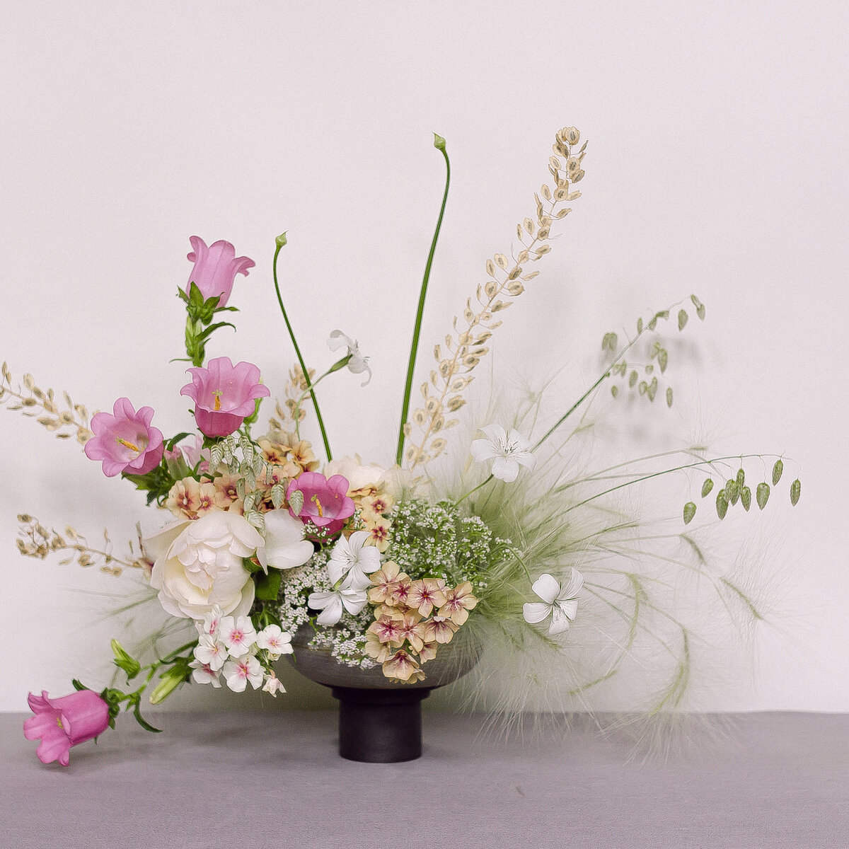 An airy arrangement of pastel flowers and lush greenery on a grey floor at a Montreal wedding. 