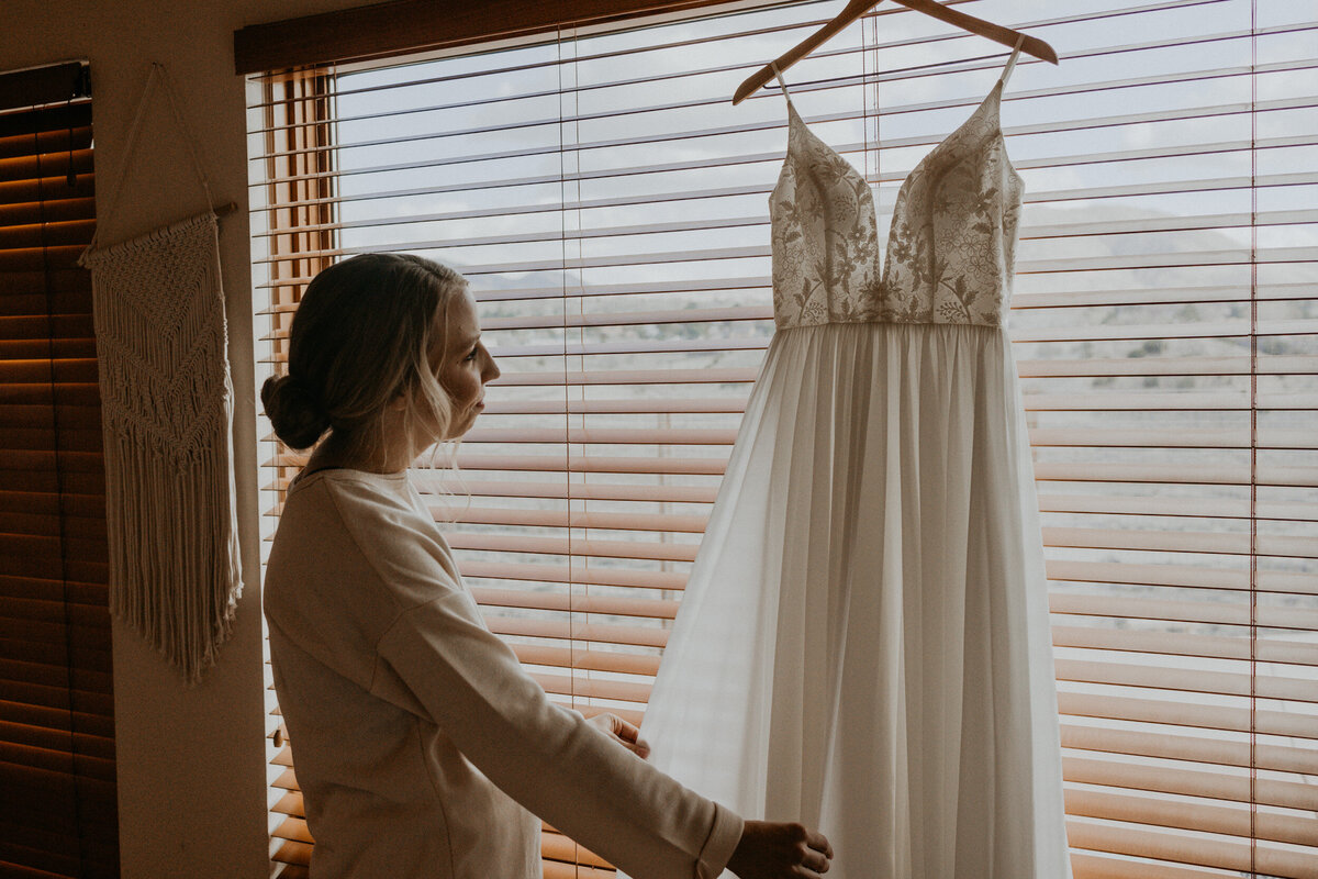 bride looking at her hanging wedding gown before the ceremony