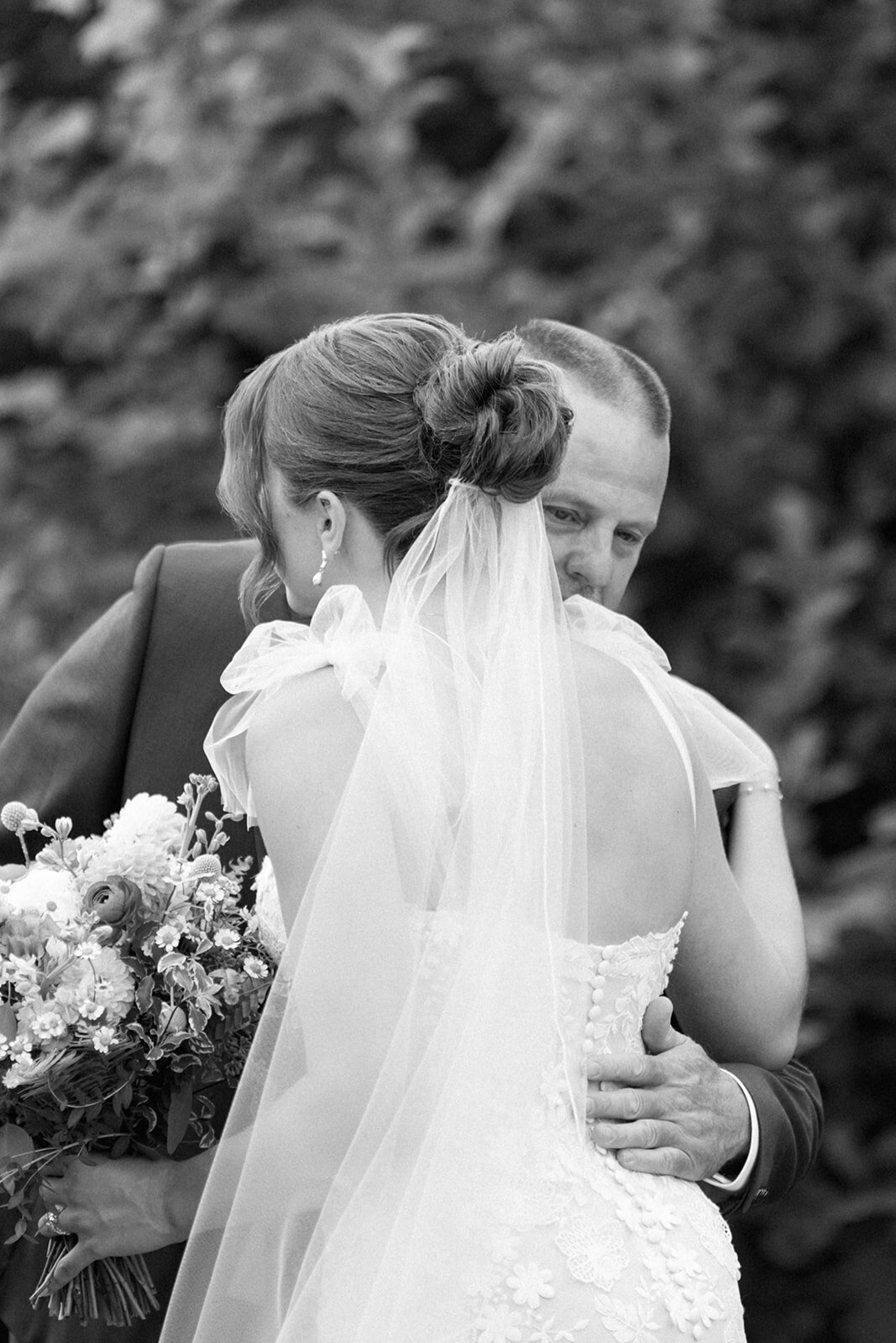 Bride and dad embracing during their emotional father-daughter first look at Nugent Orchards, a romantic fall wedding venue in Frankfort, Michigan.